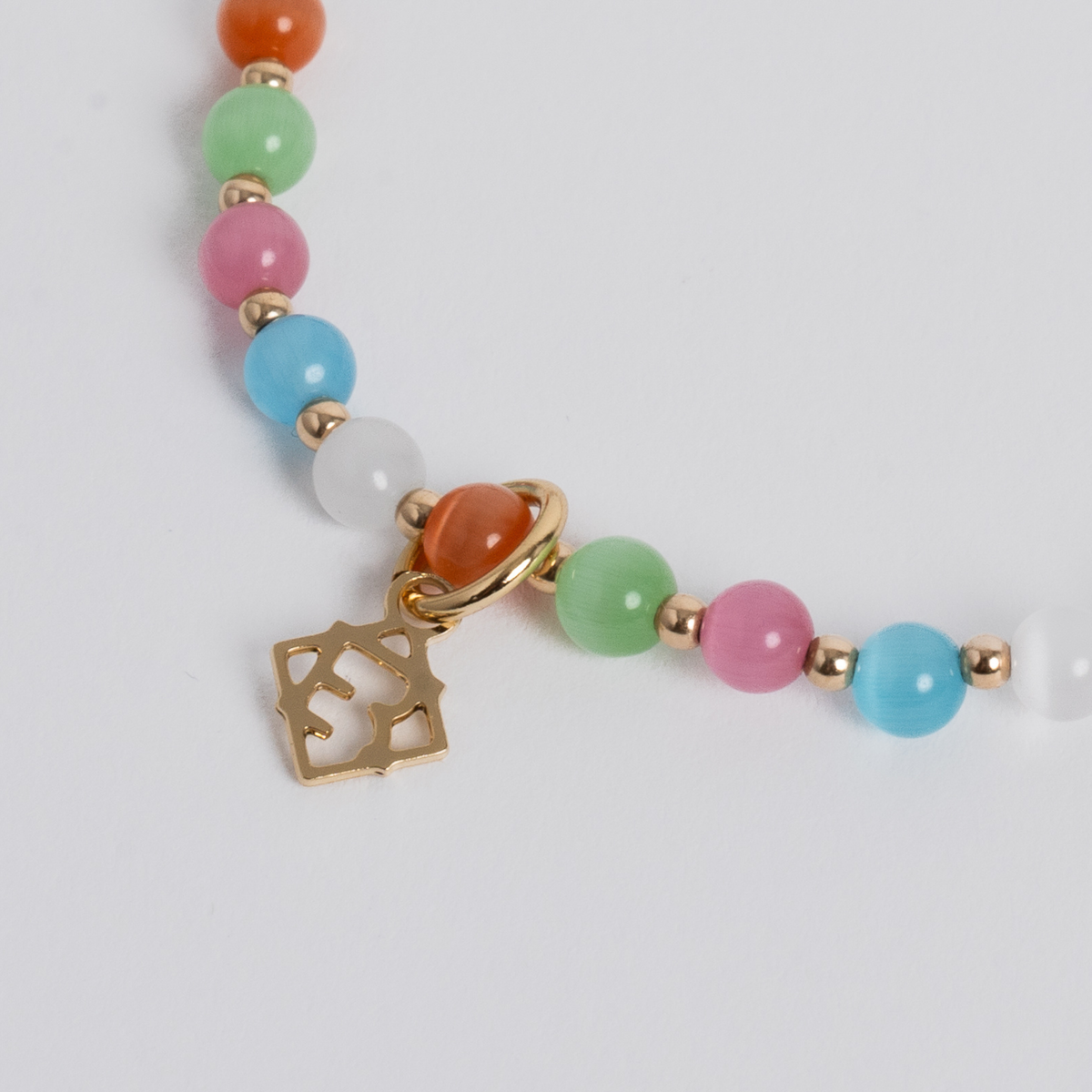 Close-up of multicolored cat’s-eye stones with 14K gold-filled beads and a golden ER charm
