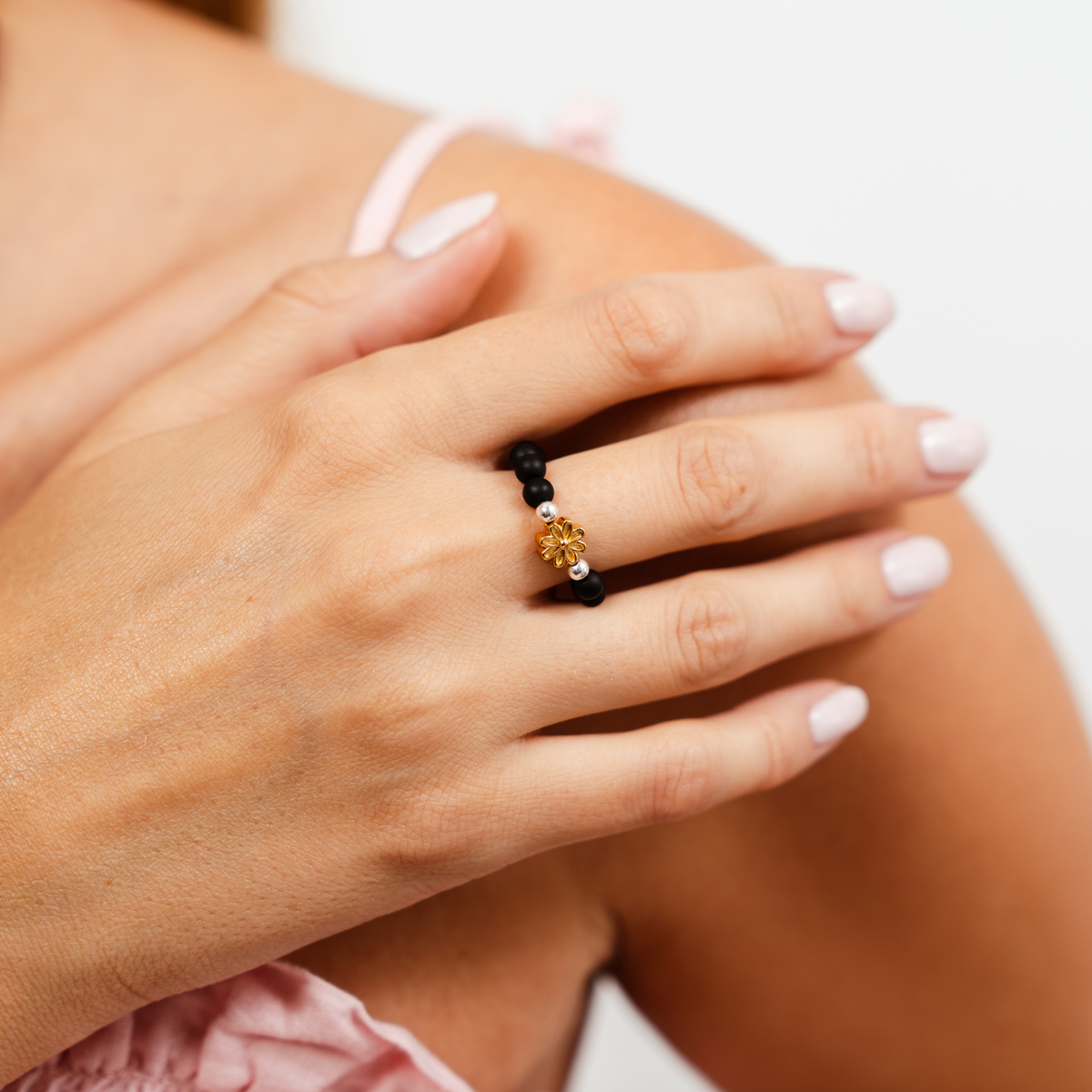 Woman wearing the Petite Fleur Ring with 4mm matte black beads, silver-filled accents and a golden flower