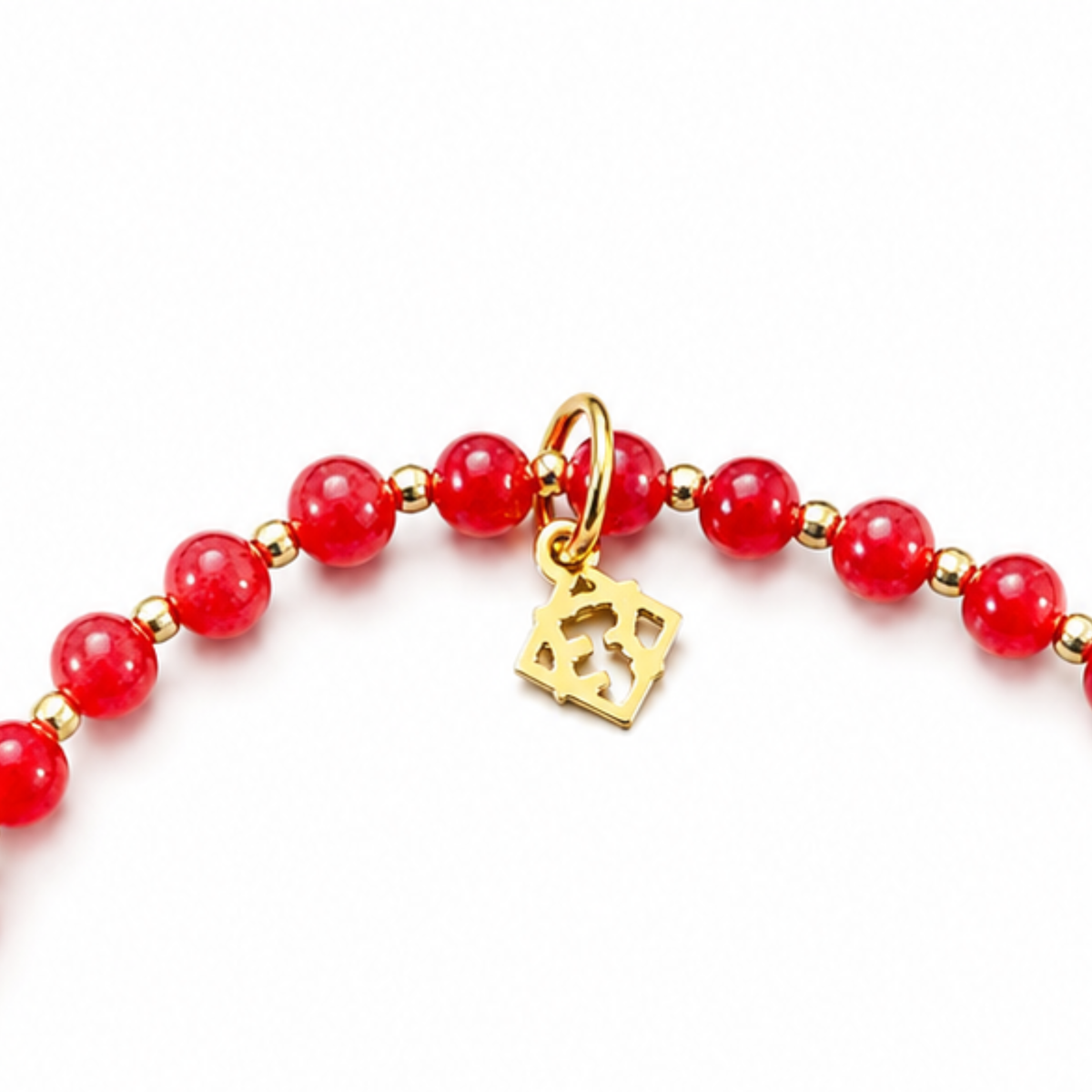 Close-up of the Prism Apple Red Bracelet with polished red jade beads, 14K gold-filled spacers and a signature golden ER charm