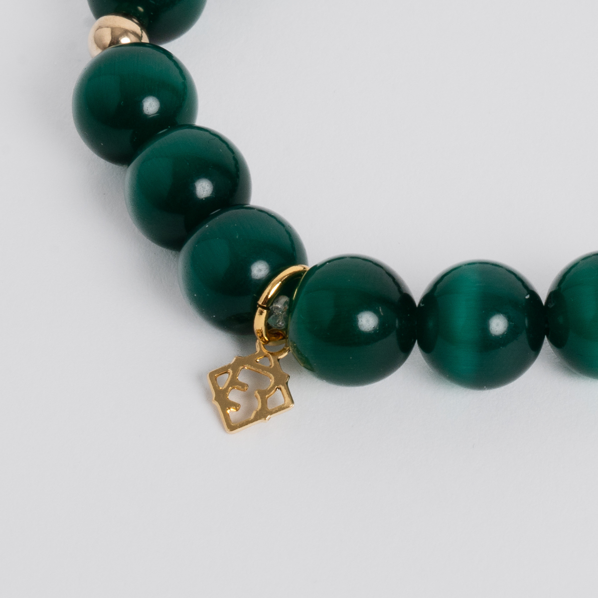 Close-up of the Prism Maxi Deep Green Bracelet with luminous cat’s-eye beads, 14K gold-filled spacers and a signature golden ER charm