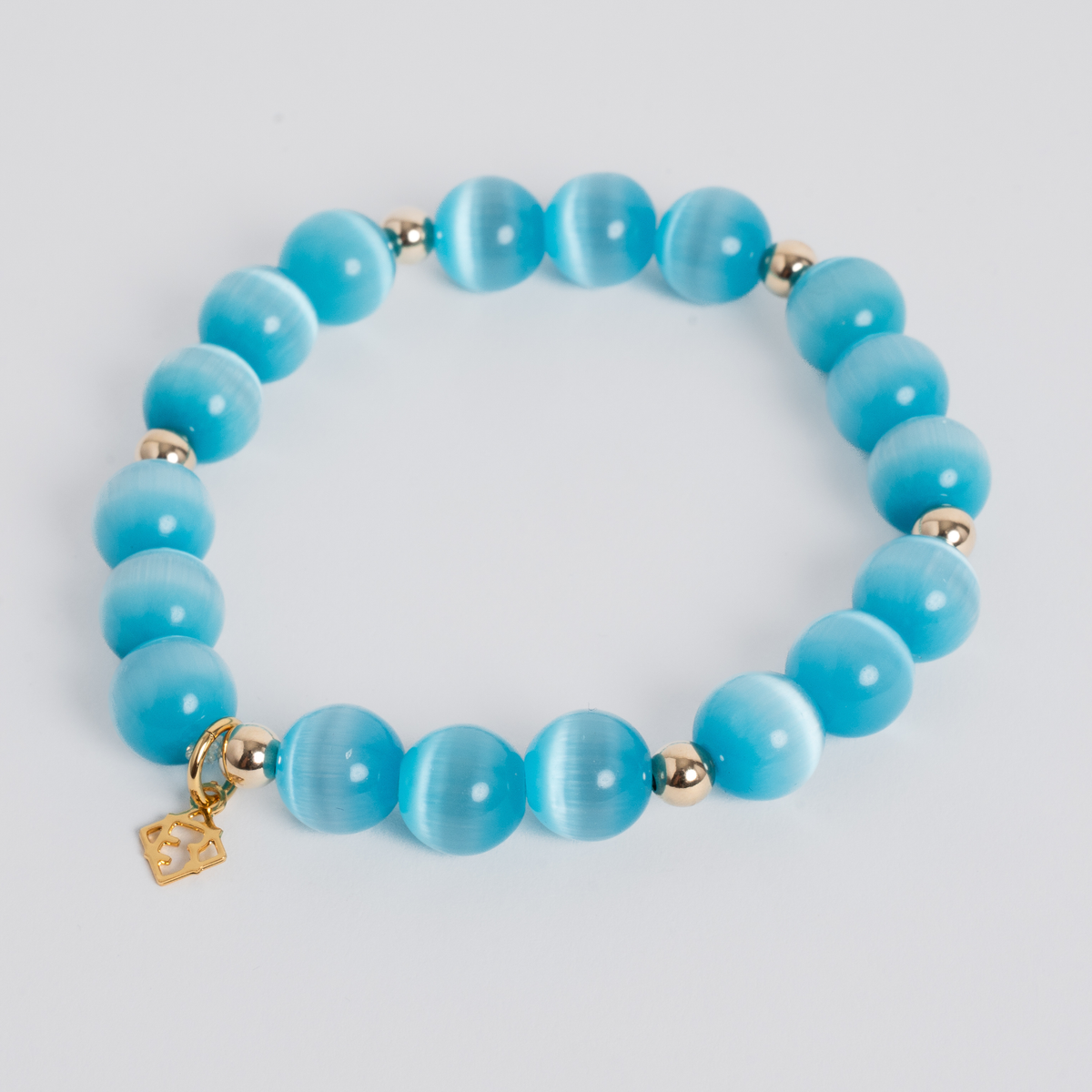 Prism Maxi Turquoise Blue stretch bracelet with 10mm cat’s-eye beads, 5mm 14K gold-filled accents and a signature golden ER charm