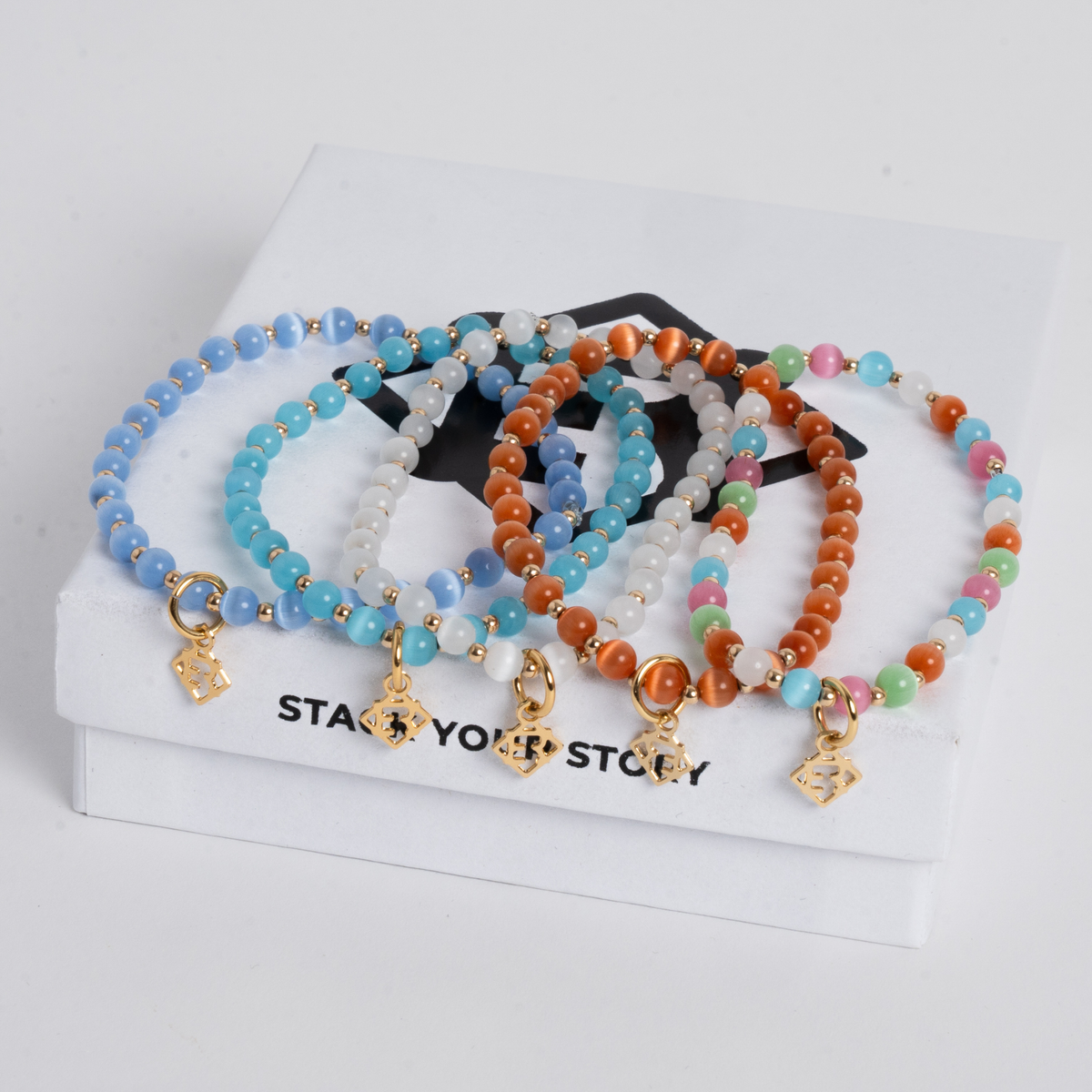 Close-up of the Prism Multi Bracelet Stack with colorful cat’s-eye stones, 14K gold-filled beads and golden ER charms