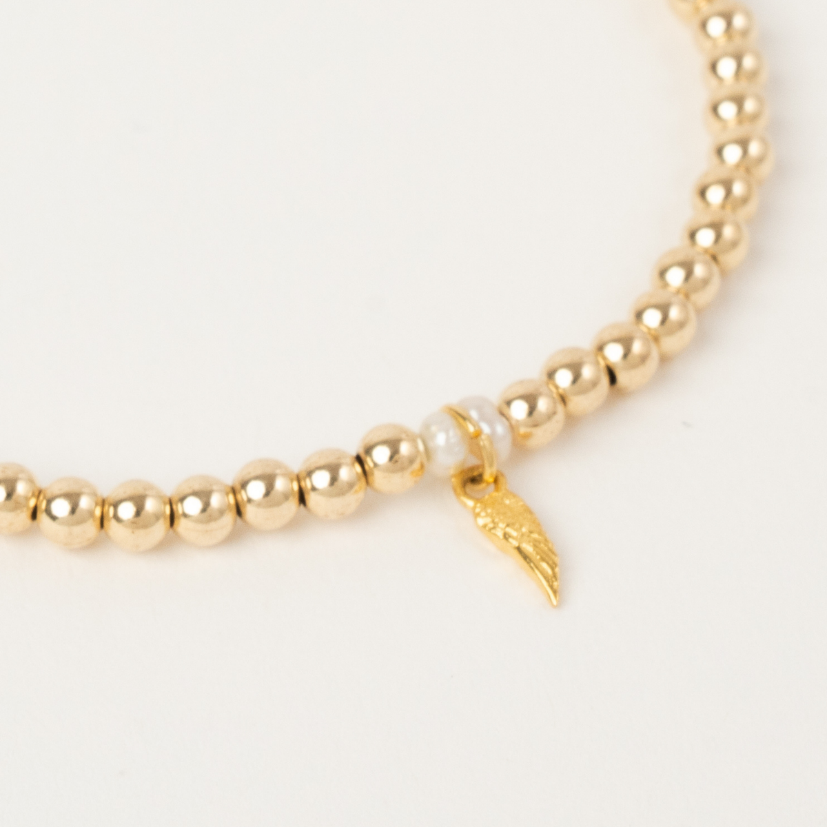 Close-up of the freshwater pearls and golden angel-wing charm on the Haven Pearl Bracelet