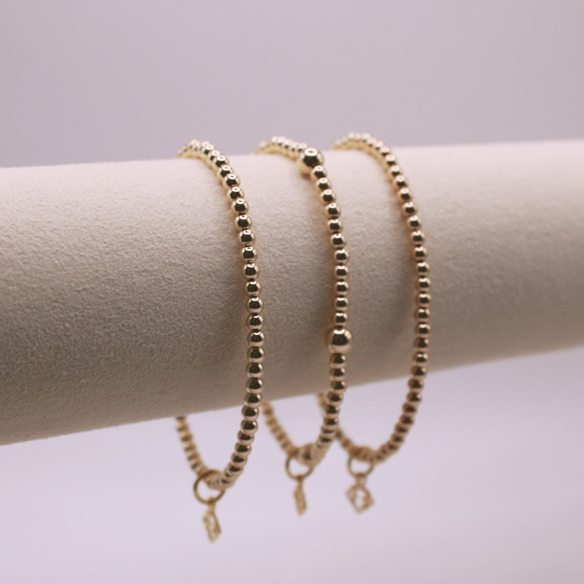 Lennon Gold Bracelet Stack with three gold-filled beaded stretch bracelets on a display stand
