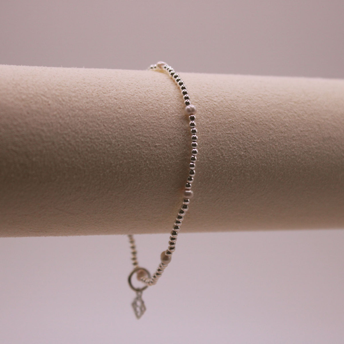 Radiance Single Bracelet in silver with evenly spaced white pearls and an ElyseRyan charm
