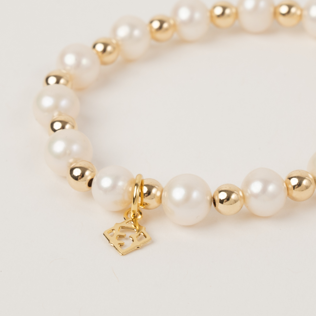 Close-up of freshwater pearls, 14K gold-filled beads and the signature charm on the Sincerity bracelet