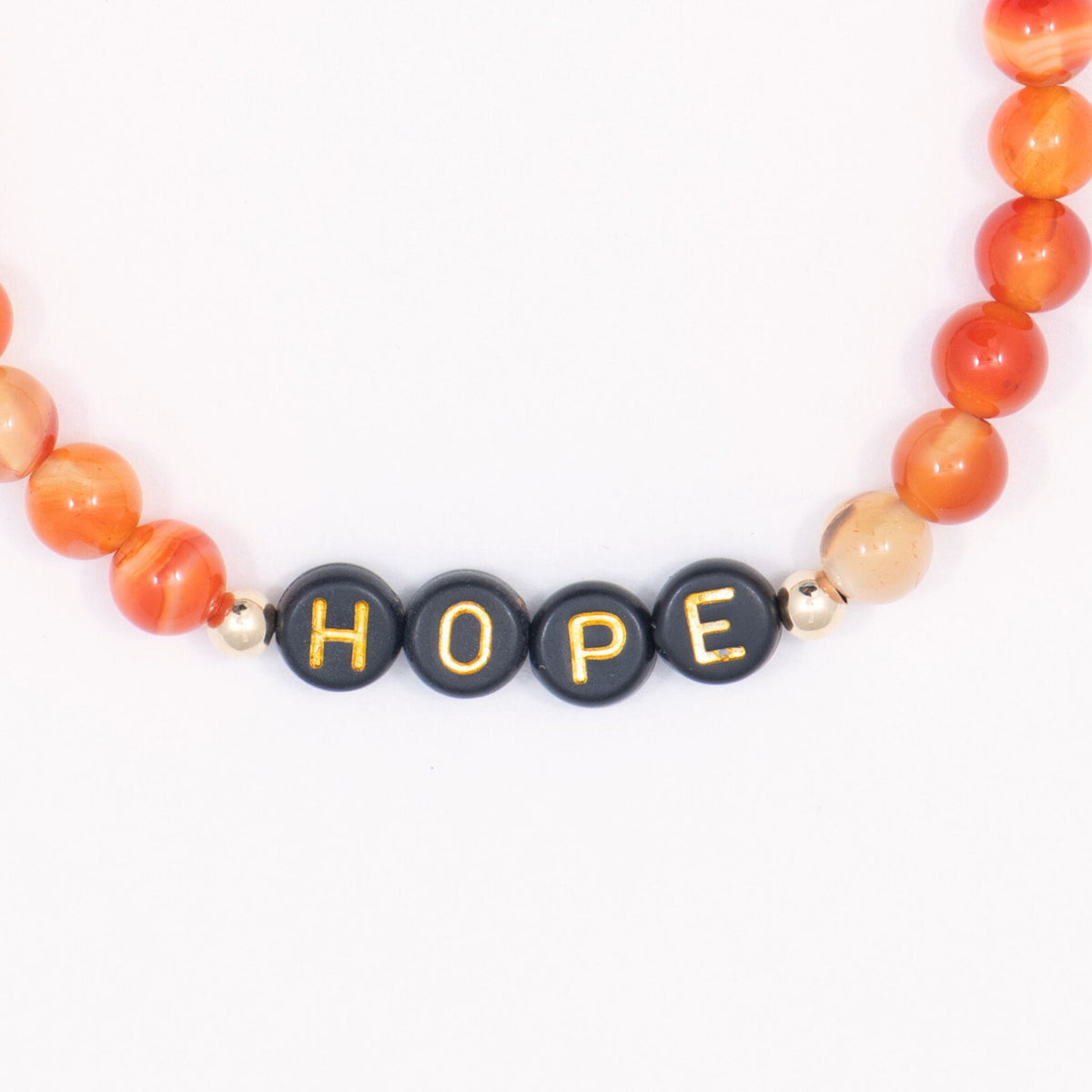 Close-up of black beads spelling HOPE between orange beads on the SU2C bracelet